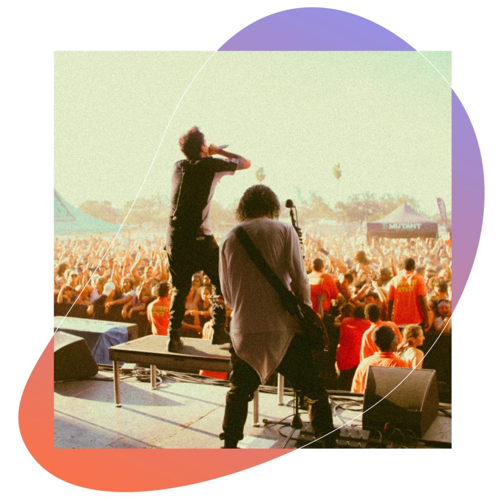 Band performs on a stage. The audience dances.